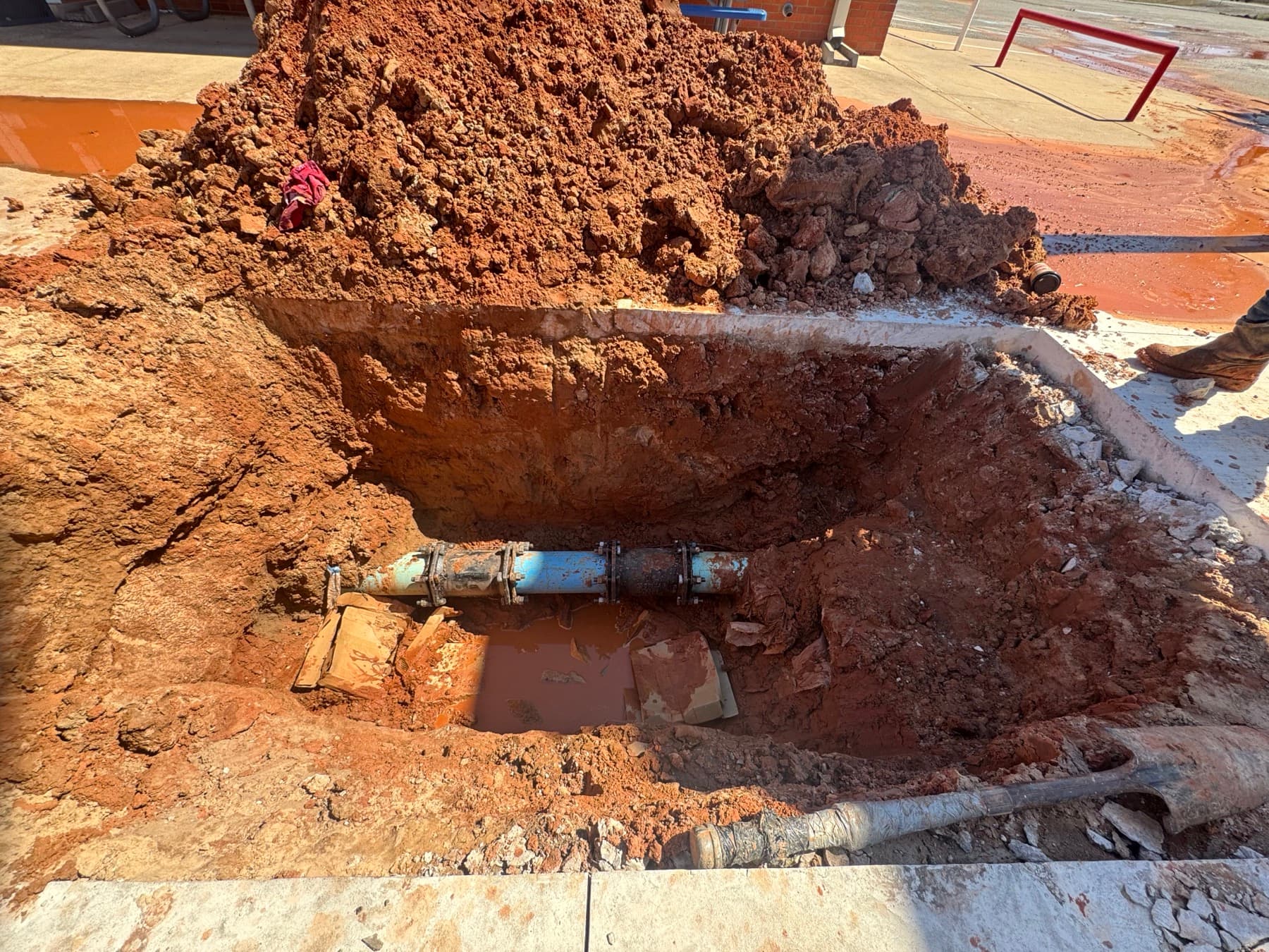 An excavation exposing a buried water line for repair work.